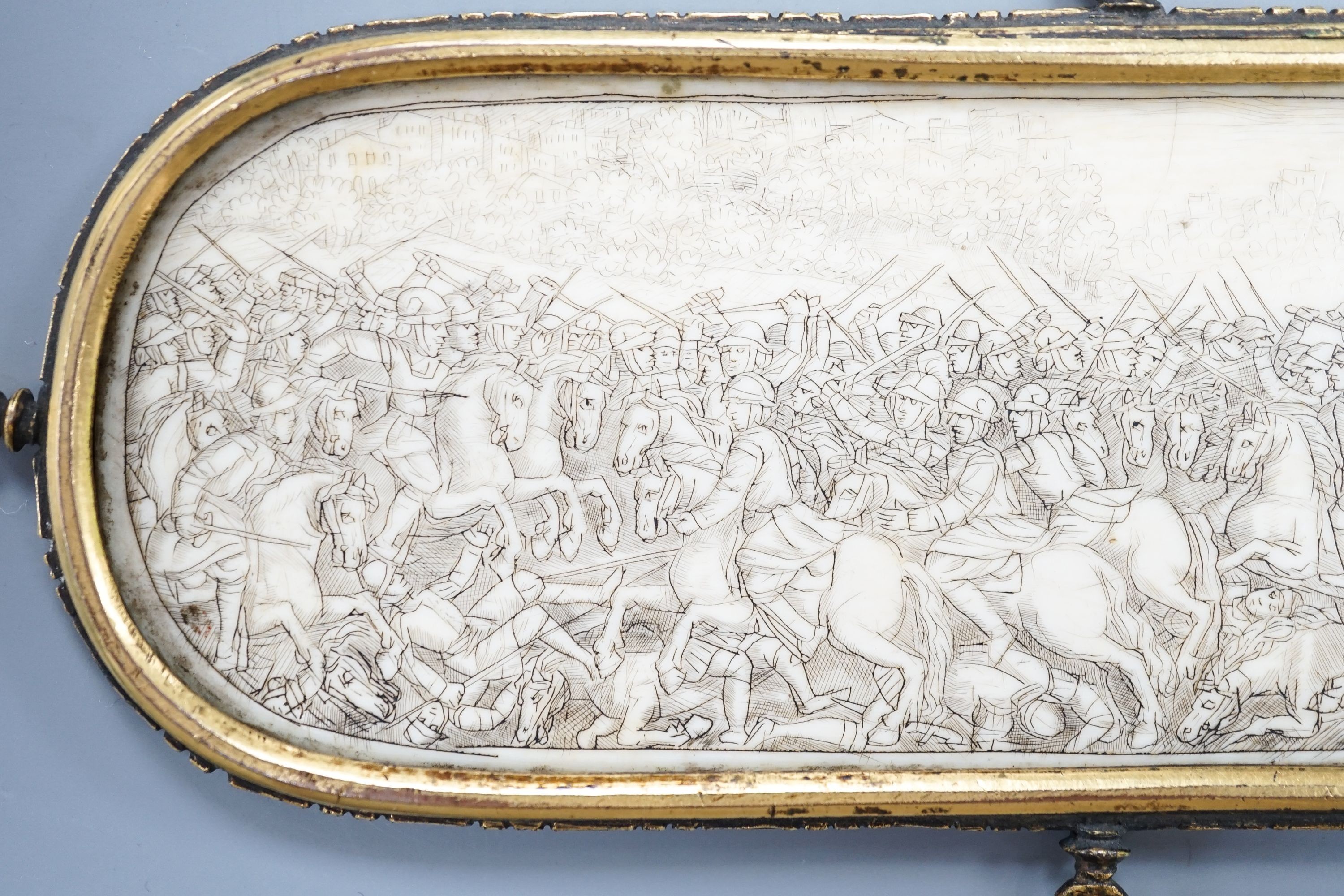 A 17th century French oval ivory plaque in a revolving metal surround, etched on both sides with battle scenes and ships in the background 17cm